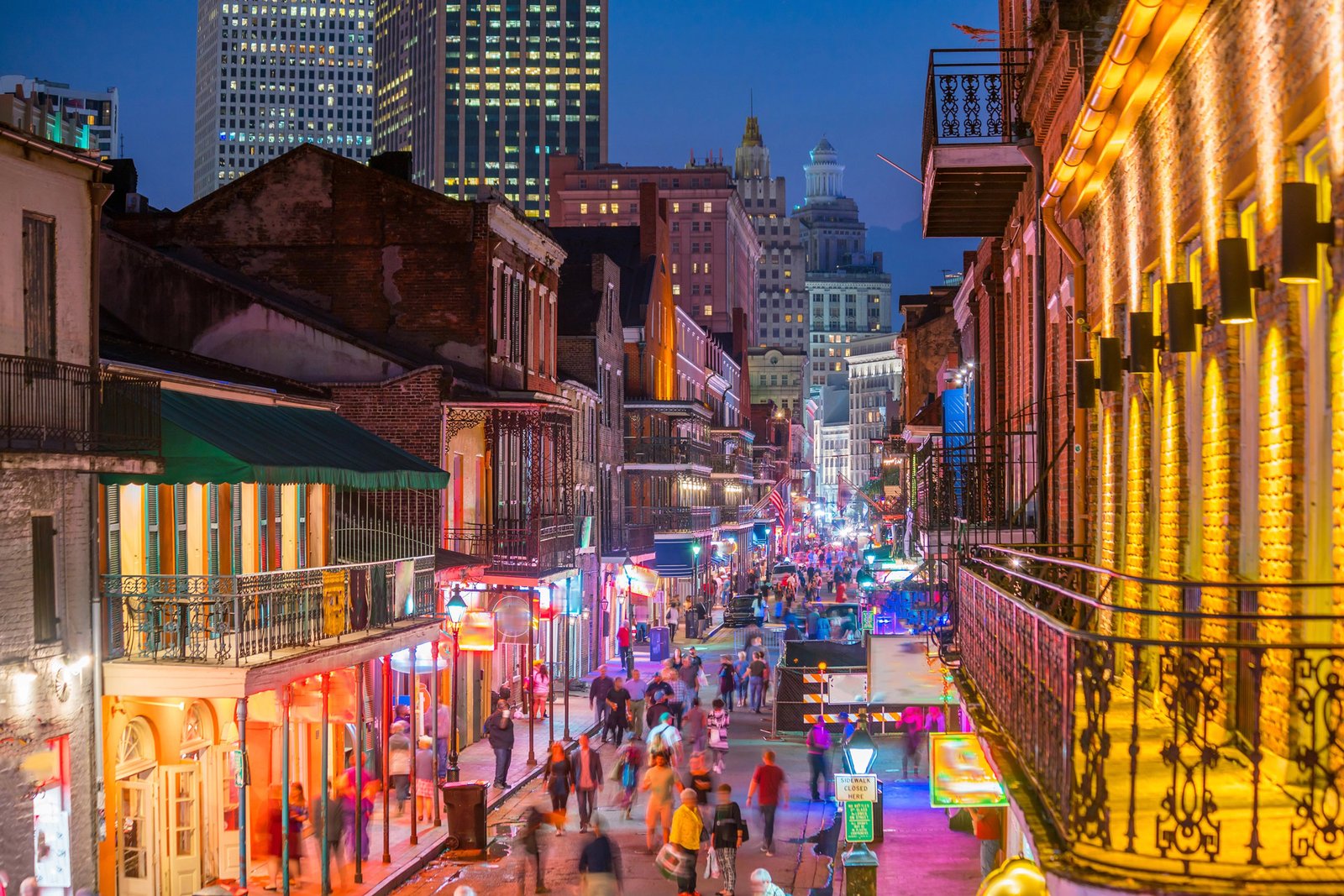 Bourbon Street at night with neon signs and wrought iron balconies above the crowd