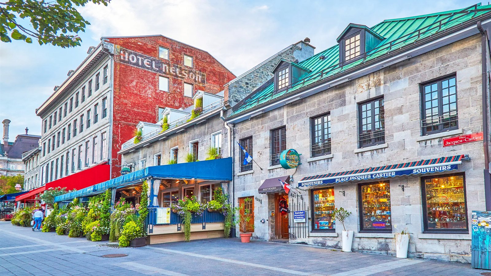 Old Montreal street lined with stone and brick buildings, shopfronts and cafes