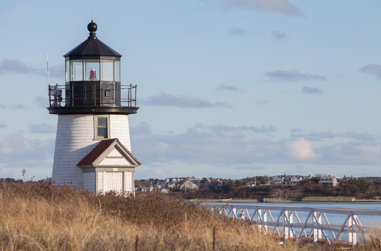 White wooden lighthouse with a shingled keeper's house under a clear sky