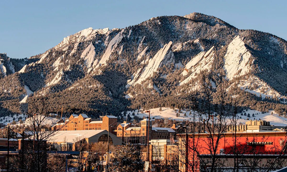 The Flatirons dusted with snow above the university campus at sunrise