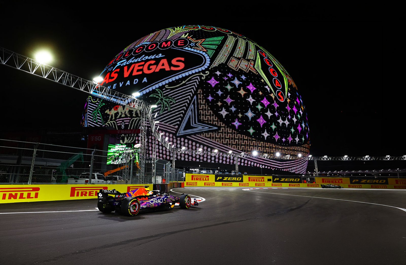 Formula 1 car passing the Sphere on the floodlit Las Vegas street circuit at night