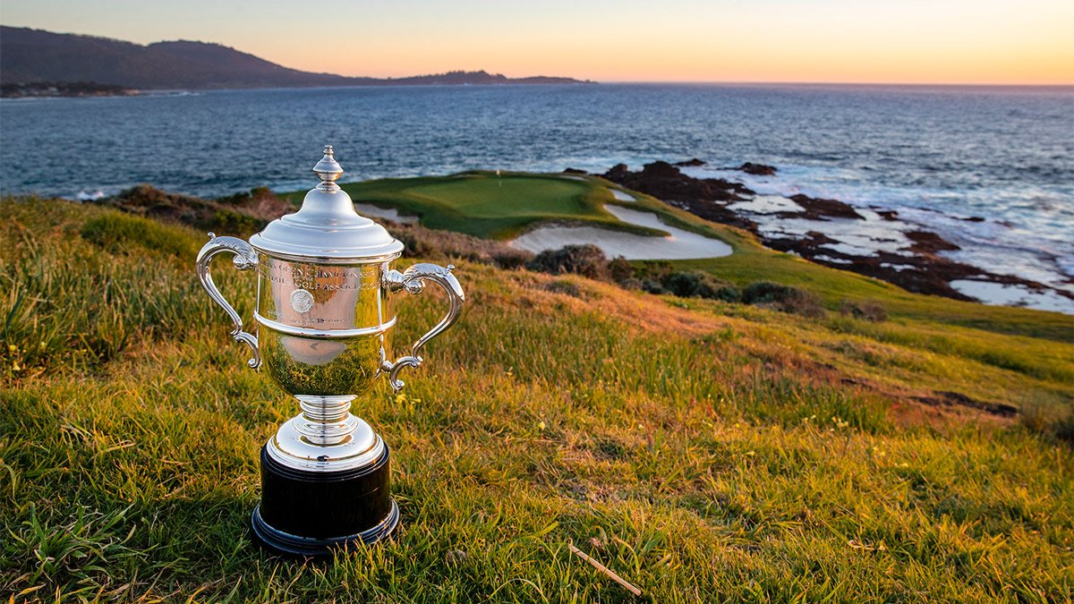 The U.S. Open trophy on the grass beside a coastal green at Pebble Beach